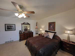 Bedroom featuring light colored carpet, ceiling fan, visible vents, and baseboards