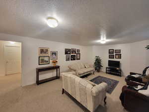 Living area with baseboards, light carpet, and a textured ceiling