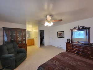 Bedroom featuring visible vents, a closet, light carpet, ensuite bathroom, and a ceiling fan