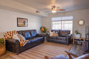 Living room with ceiling fan, wood finished floors, and visible vents