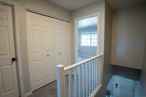 Hallway with carpet floors and an upstairs landing