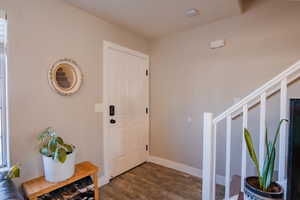 Foyer featuring baseboards and dark wood-style flooring
