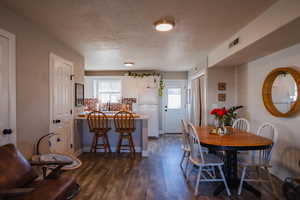 Dining area featuring a textured ceiling, visible vents, and dark wood-type flooring