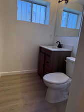 Bathroom featuring baseboards, wood finished floors, toilet, and vanity