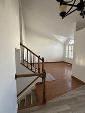 Stairway featuring baseboards, vaulted ceiling, and wood finished floors