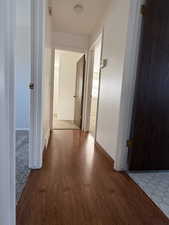 Hall featuring baseboards, visible vents, and wood finished floors