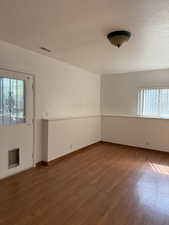 Unfurnished room featuring baseboards, wood finished floors, and visible vents