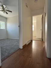 Unfurnished room featuring a ceiling fan, baseboards, visible vents, and wood finished floors