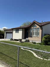 Ranch-style home featuring a garage, fence, brick siding, and a front yard