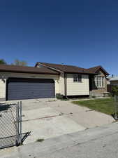 Ranch-style home featuring concrete driveway, an attached garage, fence, and a front yard