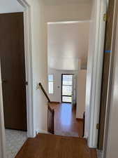 Hall with baseboards, wood finished floors, and an upstairs landing
