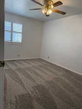 Carpeted empty room with baseboards and ceiling fan