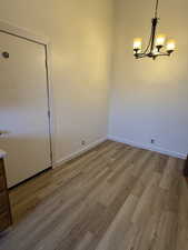 Unfurnished dining area featuring baseboards, a notable chandelier, and wood finished floors