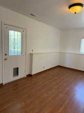 Unfurnished room featuring baseboards, wood finished floors, and visible vents