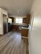 Kitchen with a sink, light countertops, stainless steel appliances, baseboards, and light wood-type flooring