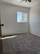 Carpeted empty room with baseboards and a ceiling fan