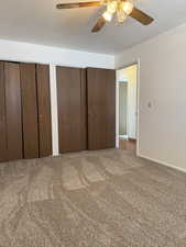 Bedroom featuring baseboards, a ceiling fan, two closets, and carpet flooring