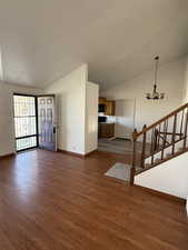 Unfurnished living room with baseboards, a notable chandelier, and vaulted ceiling