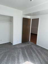 Unfurnished bedroom with baseboards, carpet, and a closet