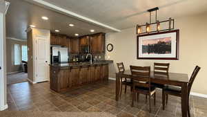 Kitchen with a textured ceiling, appliances with stainless steel finishes, baseboards, recessed lighting, and a peninsula