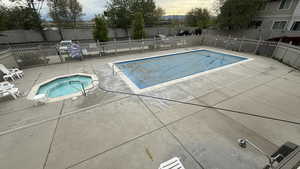 CLUB HOUSE: Pool at dusk with a community pool, fence, a hot tub, and a patio area