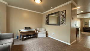 Sitting room with baseboards, ornamental molding, and a textured ceiling