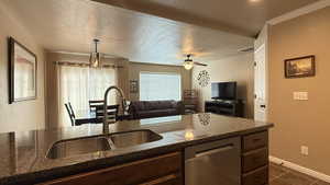 Kitchen with dark stone counters, a sink, ceiling fan, dishwasher