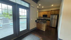 CLUB HOUSE: Kitchen with recessed lighting, brown cabinetry, stainless steel appliances, countertops, and a peninsula