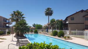 Community pool with a patio and fence