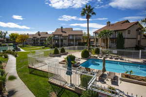 Community pool with a patio, fence, and a residential view