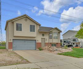 Split foyer home featuring an attached garage, driveway, and brick siding
