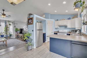 Kitchen featuring appliances with stainless steel finishes, light countertops, a peninsula, lofted ceiling, and under cabinet range hood