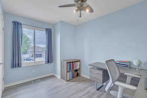 Office space with a ceiling fan, a textured ceiling, visible vents, wood finished floors, and baseboards
