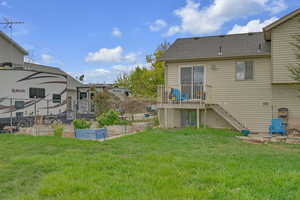 Back of property with a garden, a deck, a shingled roof, a yard, and stairway