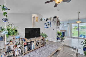 Living room featuring a textured ceiling, a ceiling fan, baseboards, vaulted ceiling, and visible vents