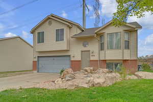 Split foyer home with brick siding, a garage, and concrete driveway