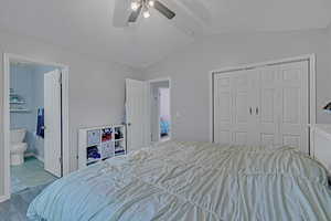 Bedroom featuring a closet, lofted ceiling, wood finished floors, a textured ceiling, and ensuite bath