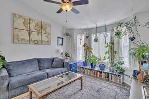 Living room featuring a textured ceiling, ceiling fan, wood finished floors, and visible vents