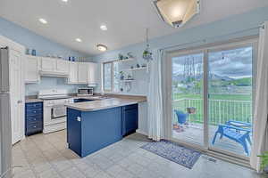Kitchen featuring stainless steel appliances, white cabinetry, a peninsula, light floors, and under cabinet range hood