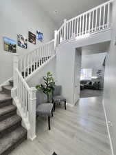 Staircase with baseboards, a towering ceiling, wood finished floors, and visible vents
