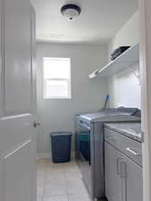 Laundry room with visible vents, light tile patterned flooring, a textured ceiling, cabinet space, and independent washer and dryer