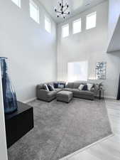 Living room with baseboards, a high ceiling, a notable chandelier, and visible vents