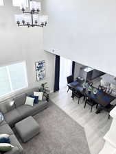 Living area featuring a chandelier, wood finished floors, visible vents, and a towering ceiling