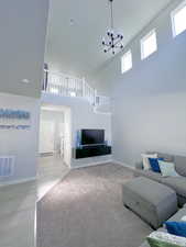 Living area featuring visible vents, a towering ceiling, wood finished floors, baseboards, and a notable chandelier