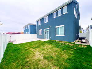 Rear view of house featuring a yard, a patio, a fenced backyard, and stucco siding