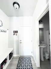 Mudroom with baseboards, a textured ceiling, and light wood-style flooring