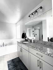 Bathroom featuring vanity, a textured ceiling, a bath, tile patterned floors, and a stall shower