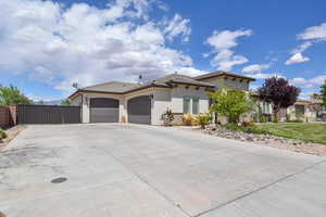 View of front of home featuring a tiled roof, a gate, concrete driveway, an attached garage, and stucco siding