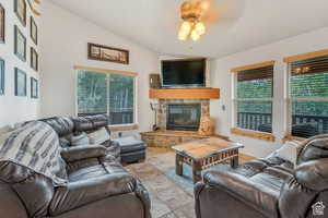 Tiled living room with a fireplace, a ceiling fan, and lofted ceiling