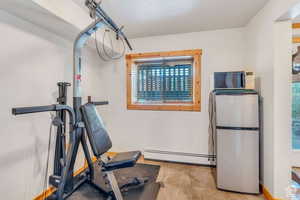 Exercise area featuring baseboards, baseboard heating, and tile patterned floors